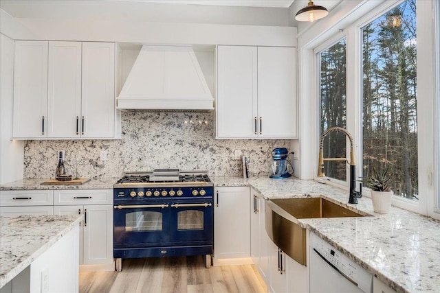 kitchen featuring premium range hood, double oven range, sink, and white cabinets