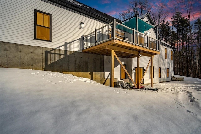 snow covered back of property featuring a deck