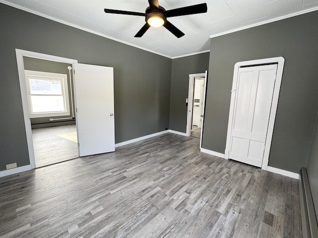 unfurnished bedroom with crown molding, a baseboard radiator, ceiling fan, and light wood-type flooring