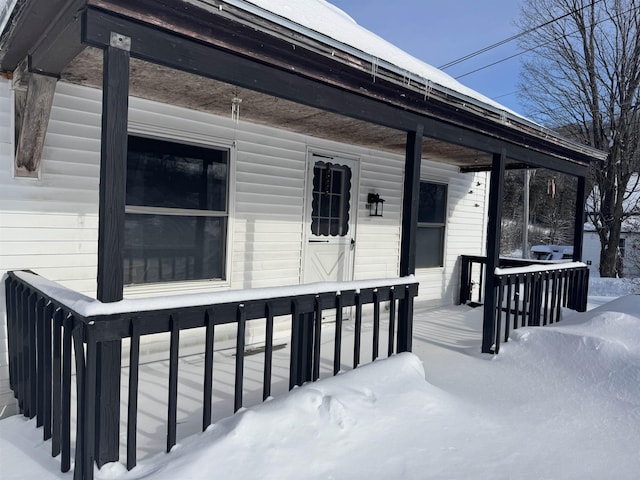 snow covered property entrance with a porch