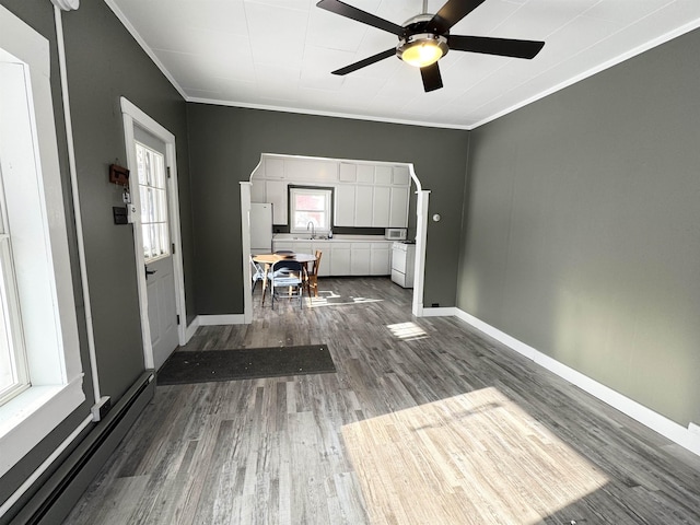 interior space featuring dark wood-type flooring, sink, baseboard heating, ornamental molding, and ceiling fan