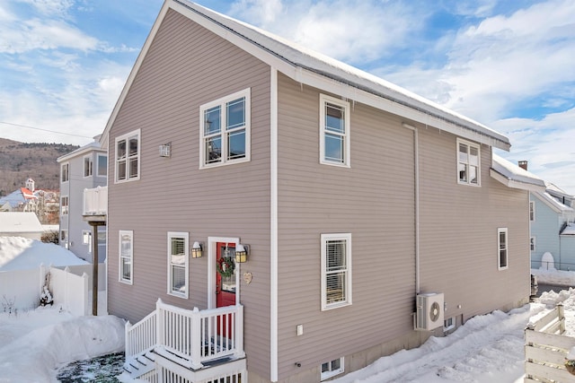 snow covered house featuring ac unit