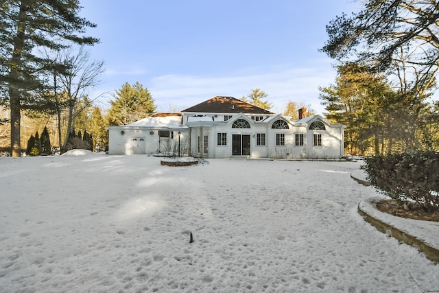 snow covered back of property with a garage