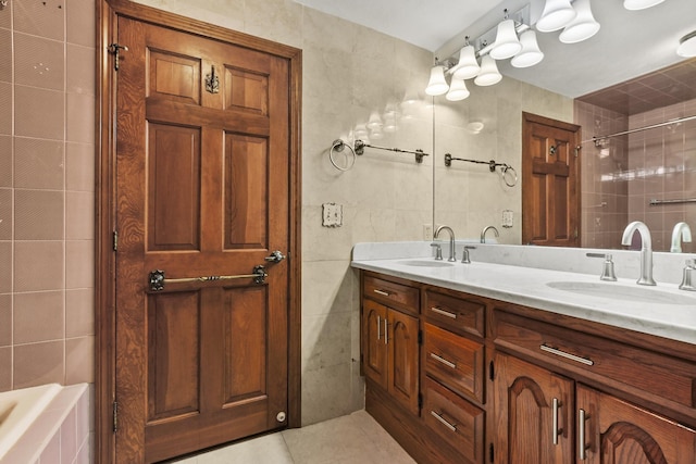 bathroom with a bath, vanity, tile walls, and tile patterned floors