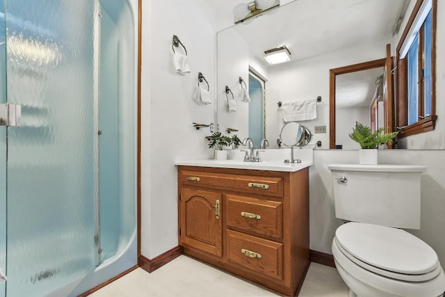 bathroom featuring vanity, a shower with shower door, and toilet