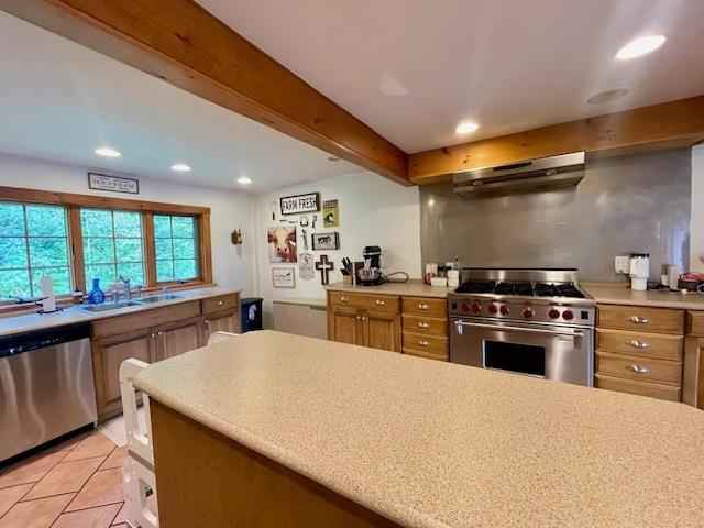 kitchen featuring sink, beam ceiling, stainless steel appliances, and light tile patterned flooring