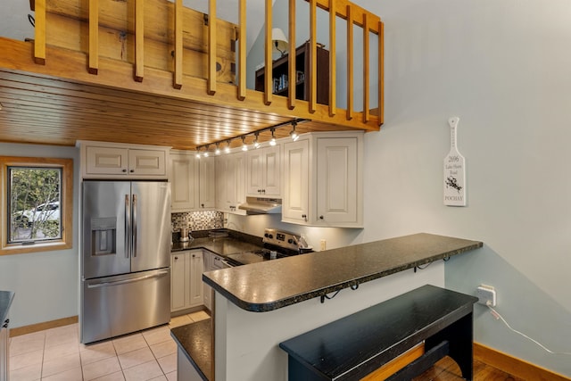 kitchen featuring light tile patterned flooring, tasteful backsplash, appliances with stainless steel finishes, kitchen peninsula, and white cabinets