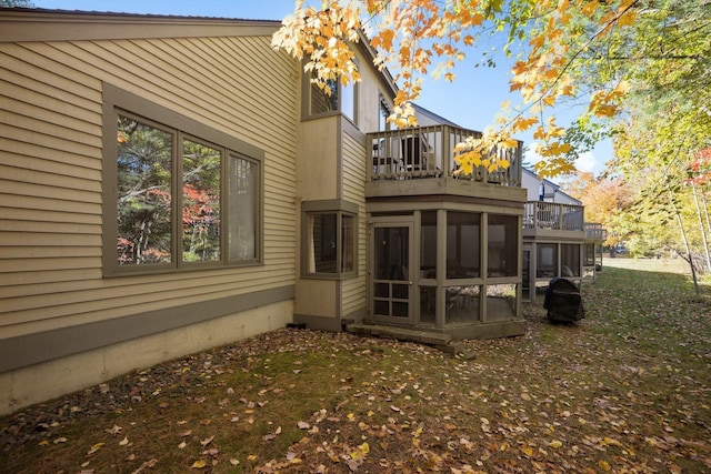 back of property featuring a yard and a sunroom