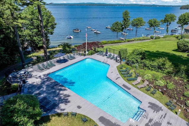 view of pool featuring a patio, a water view, and a lawn