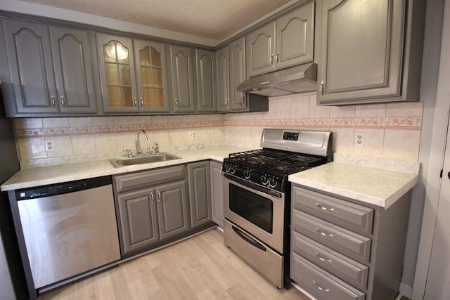 kitchen featuring sink, gray cabinets, appliances with stainless steel finishes, tasteful backsplash, and light wood-type flooring