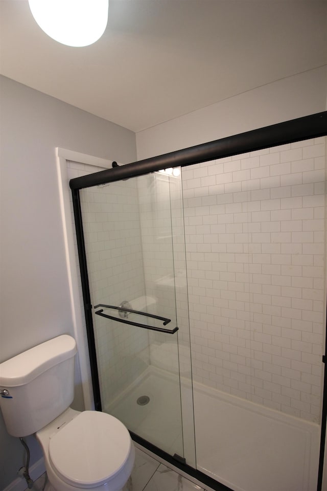 bathroom featuring a shower with shower door and toilet