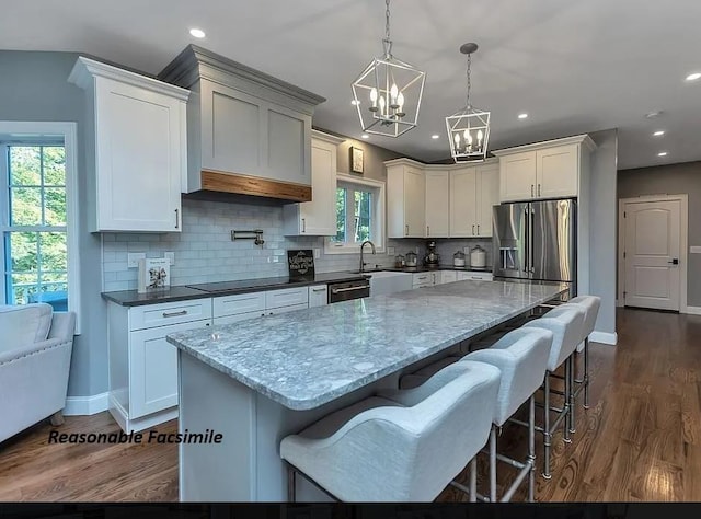 kitchen with white cabinetry, stainless steel appliances, decorative light fixtures, and a center island