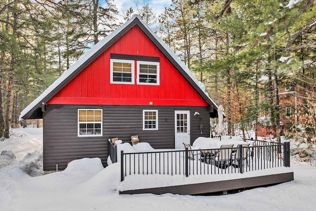 snow covered back of property with a deck