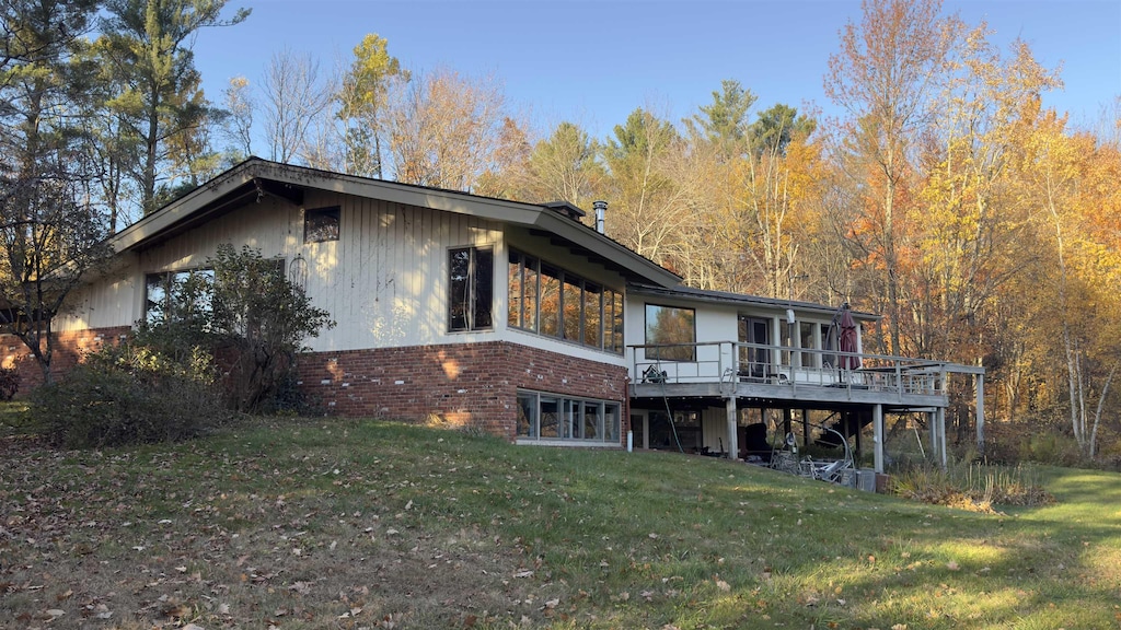 back of house with a deck and a lawn