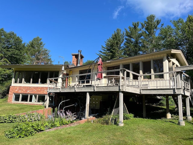 back of property with a sunroom, a yard, and a deck