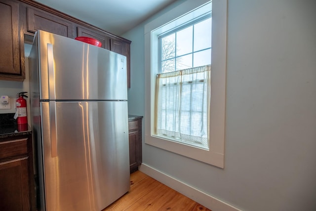 kitchen with dark brown cabinetry, stainless steel refrigerator, and light hardwood / wood-style flooring