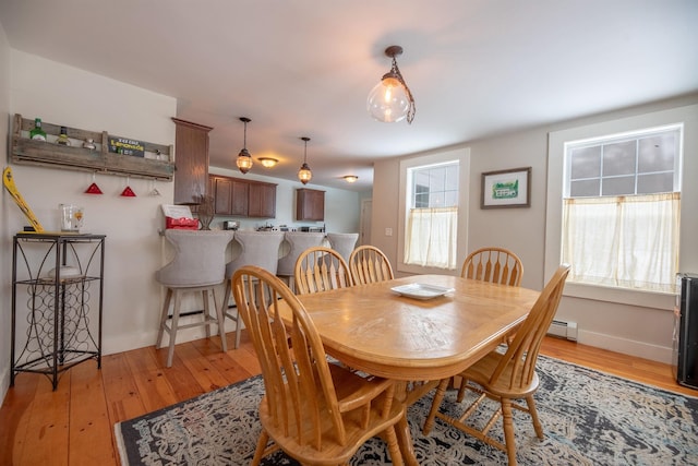 dining space with light hardwood / wood-style flooring and a baseboard radiator