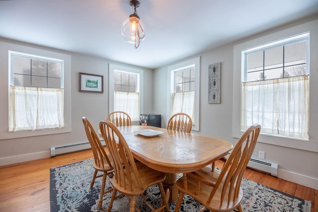 dining space featuring a baseboard heating unit and light wood-type flooring