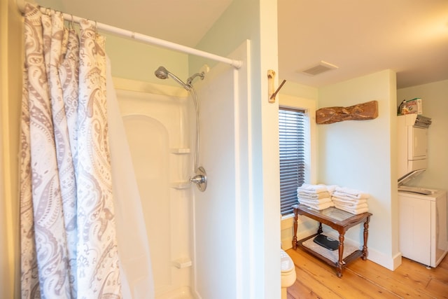 bathroom with stacked washer / drying machine, curtained shower, and wood-type flooring