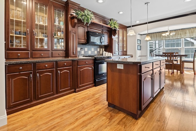 kitchen with a center island, hanging light fixtures, dark brown cabinets, and black appliances