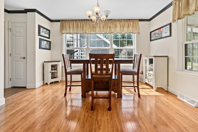 dining area with crown molding, an inviting chandelier, and light hardwood / wood-style floors