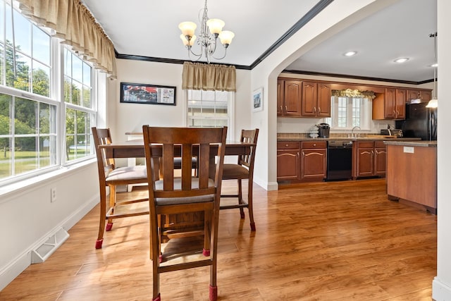 dining space featuring a notable chandelier, crown molding, sink, and hardwood / wood-style flooring