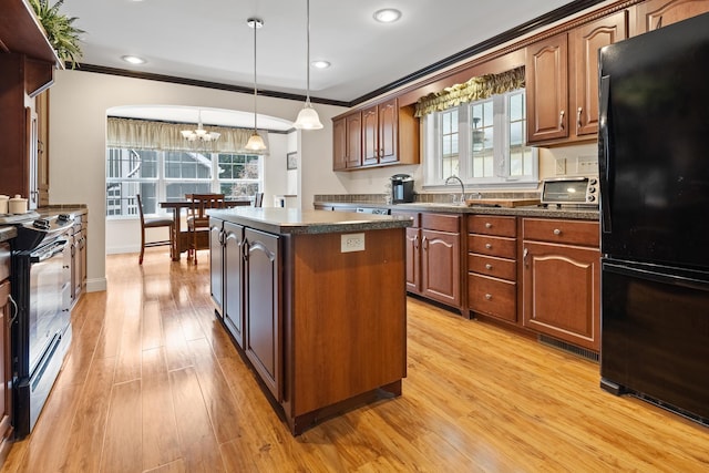 kitchen featuring black fridge, decorative light fixtures, a center island, stainless steel electric range, and light hardwood / wood-style flooring