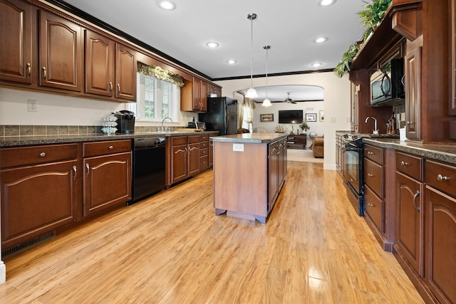 kitchen with sink, black appliances, light hardwood / wood-style floors, a kitchen island, and decorative light fixtures