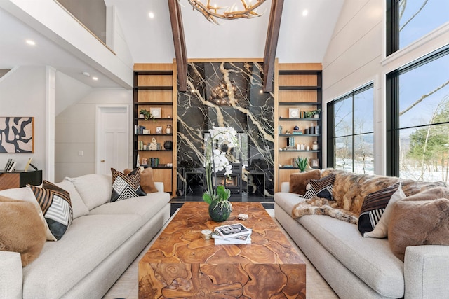 living room featuring a high end fireplace, a chandelier, high vaulted ceiling, and built in shelves