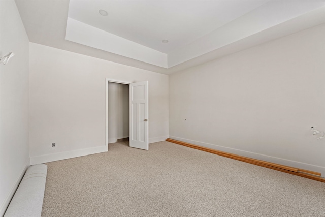 unfurnished bedroom featuring a closet, a raised ceiling, and carpet