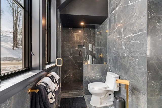 bathroom featuring toilet, a shower with door, and tile walls