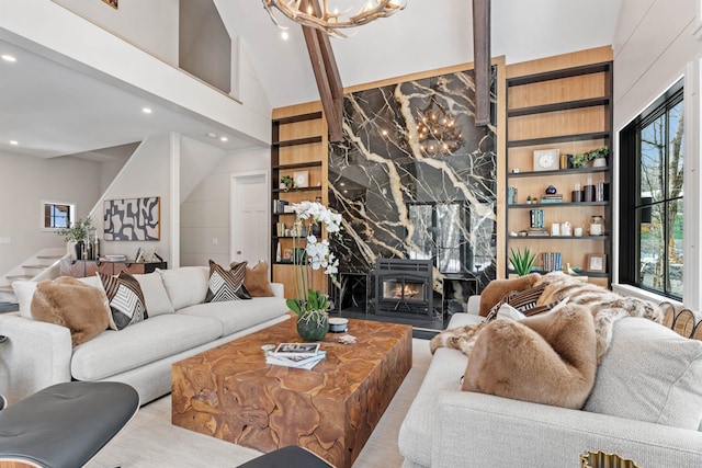 living room with high vaulted ceiling, a fireplace, built in features, and a chandelier