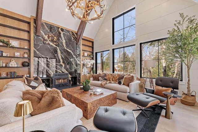 living room featuring an inviting chandelier, hardwood / wood-style floors, built in shelves, and a high ceiling