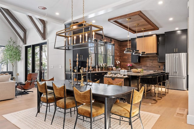 dining space with lofted ceiling with beams and light hardwood / wood-style floors