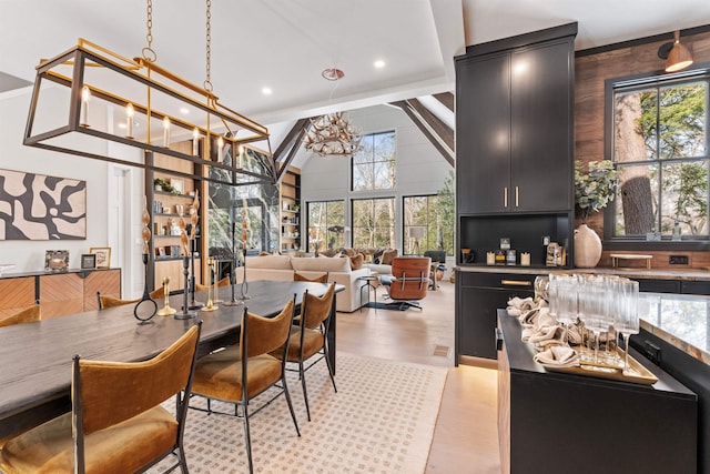 dining space with a high ceiling, light hardwood / wood-style flooring, and a notable chandelier