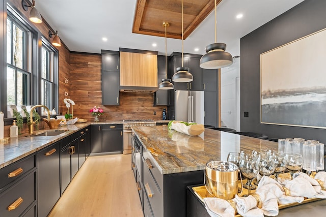 kitchen with pendant lighting, high quality appliances, sink, a center island, and light stone countertops