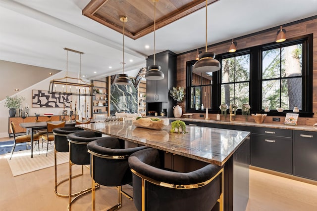 kitchen featuring hanging light fixtures, a kitchen island, a kitchen breakfast bar, and light stone counters