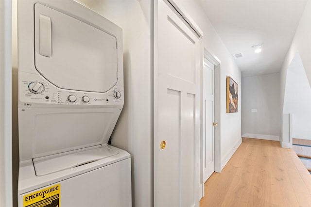 clothes washing area featuring stacked washer and dryer and light hardwood / wood-style floors