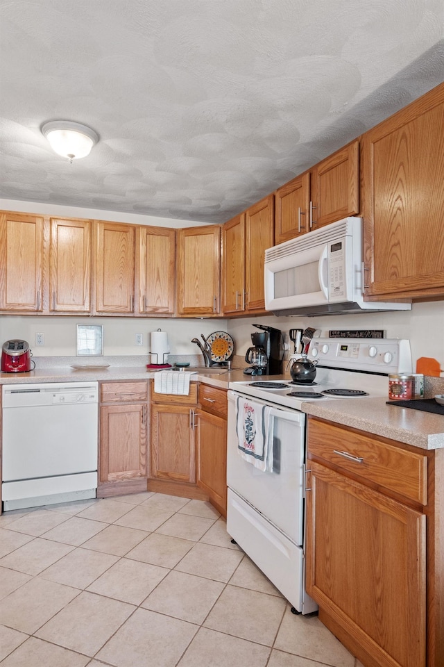 kitchen with light tile patterned flooring, sink, and white appliances