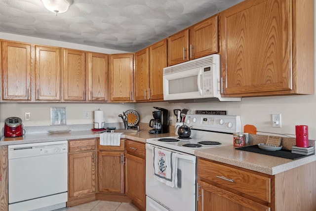 kitchen with sink, white appliances, and light tile patterned floors