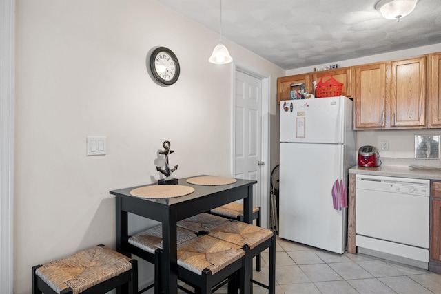 kitchen featuring pendant lighting, white appliances, and light tile patterned flooring