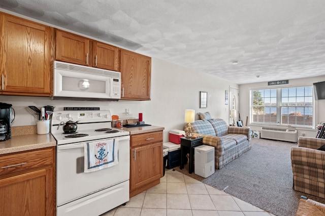 kitchen with a wall mounted AC, light carpet, a textured ceiling, and white appliances