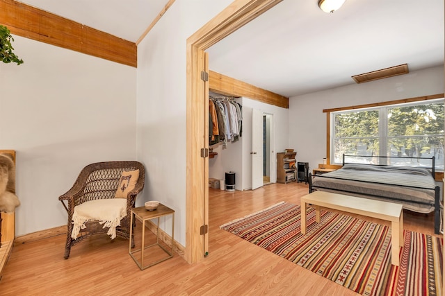 bedroom with beam ceiling and light hardwood / wood-style floors