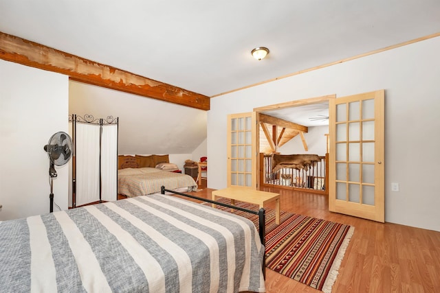 bedroom with lofted ceiling with beams and light wood-type flooring