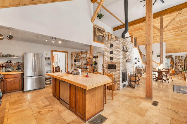 kitchen with a fireplace, high vaulted ceiling, stainless steel fridge, a kitchen island, and beam ceiling