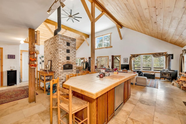 kitchen with tile countertops, beamed ceiling, a healthy amount of sunlight, and a wood stove