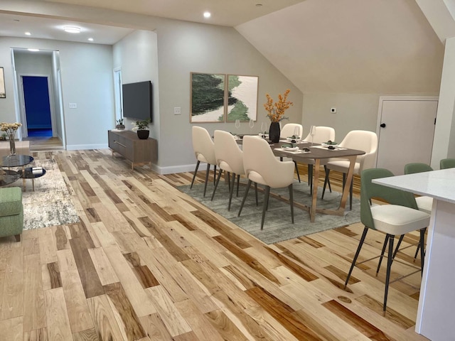 dining room with lofted ceiling and light wood-type flooring