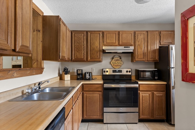 kitchen featuring appliances with stainless steel finishes, sink, light tile patterned floors, and a textured ceiling