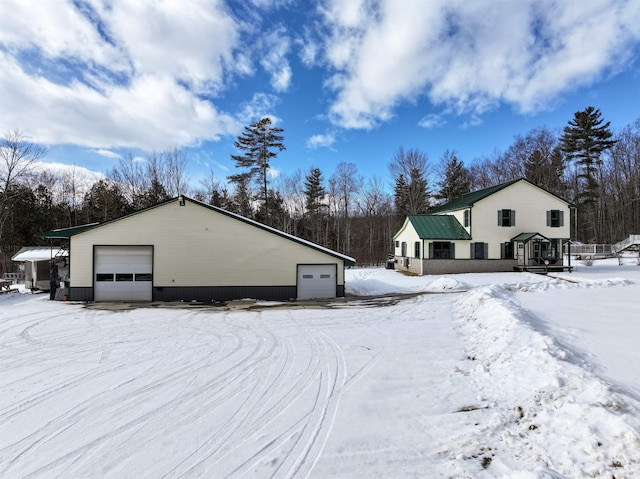 view of snowy exterior featuring a garage and an outdoor structure