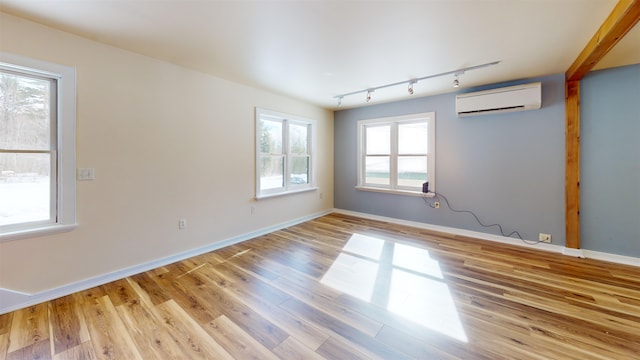 spare room featuring a wall mounted AC, track lighting, and light hardwood / wood-style floors